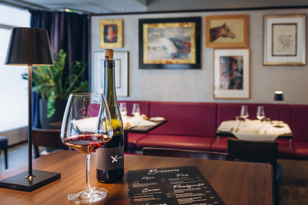 Blick ins Restaurant mit gedeckten Tischen, einem Glas Wein und Bildern an Wand im Moosburger Hof
